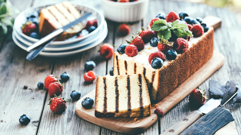 A loaf of grilled pound cake with fresh berries on a wooden table