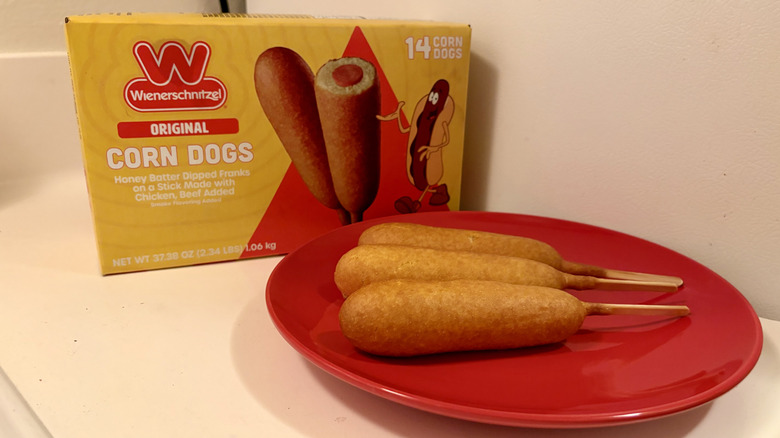 A plate of prepared Wienerschnitzel Original Corn Dogs next to the box