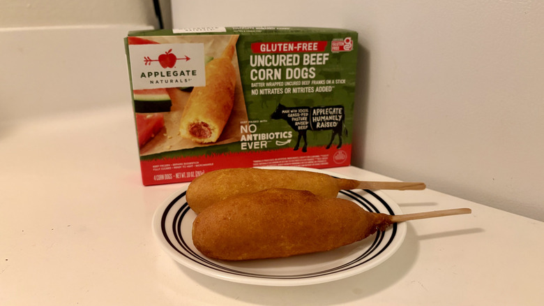 A plate of prepared Applegate Natural Corn Dogs next to the box