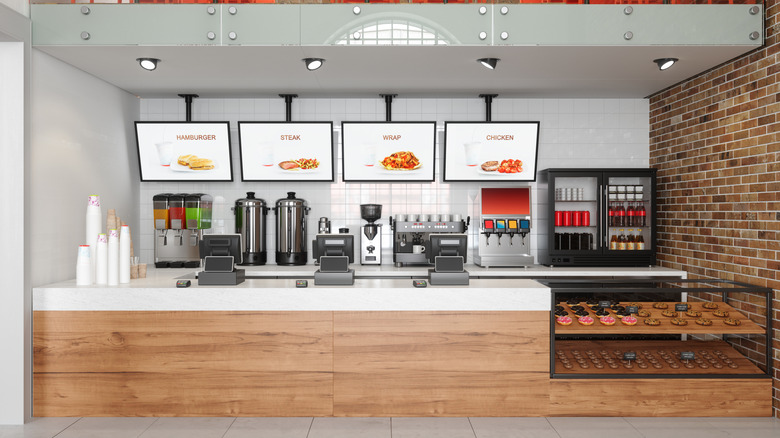 A fast food chain restaurant counter with electronic menu boards and donuts in a display counter