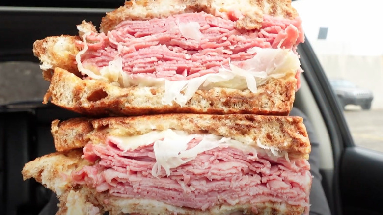 Close-up of Arby's Reuben sandwich stacked with layers of sliced corned beef, sauerkraut, and melted cheese between toasted rye bread.