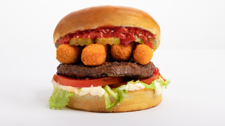 A burger with mozzarella sticks and marinara sauce