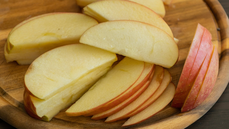 Cut up apple slices on a wood cutting board.