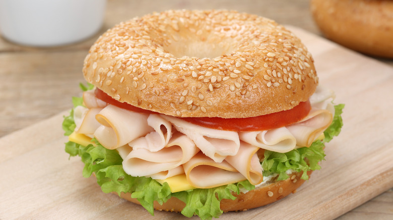 Sesame seed bagel sandwich with turkey, tomato, lettuce, and cheese.