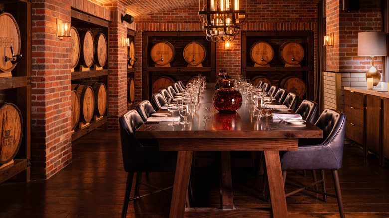 Large dining table in a brick room lined with barrels