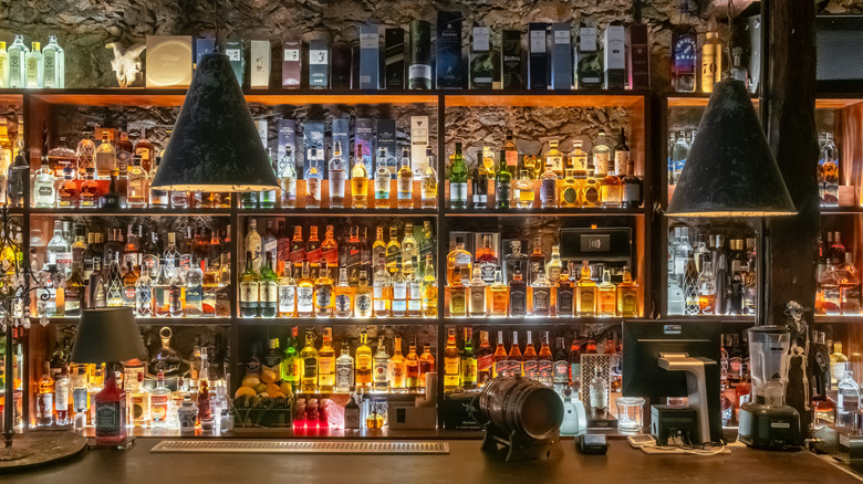 Rustic bar with shelves filled with bottles of whiskey