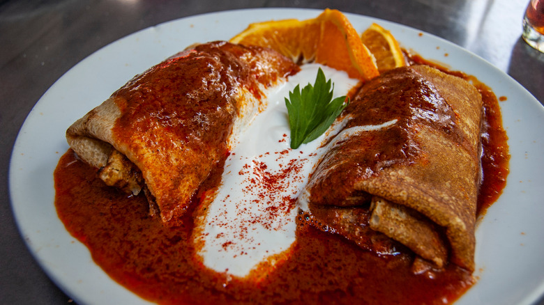 A plate of hortobágyi palacsinta topped with a paprika sauce and sour cream.