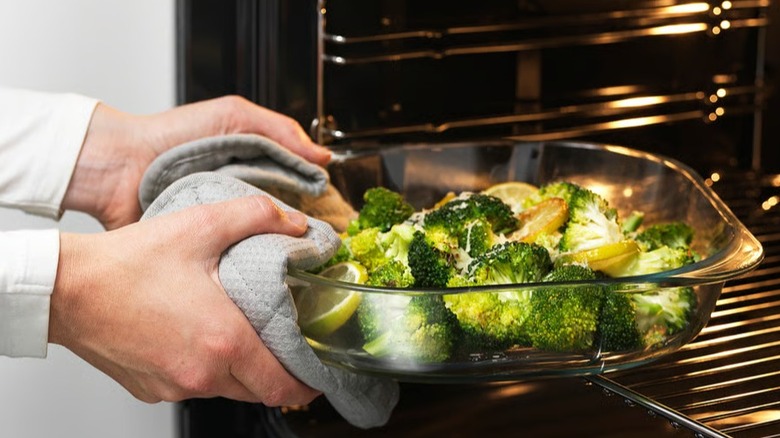 Person taking a FÖLJSAM baking dish full of cooked broccoli out of the oven