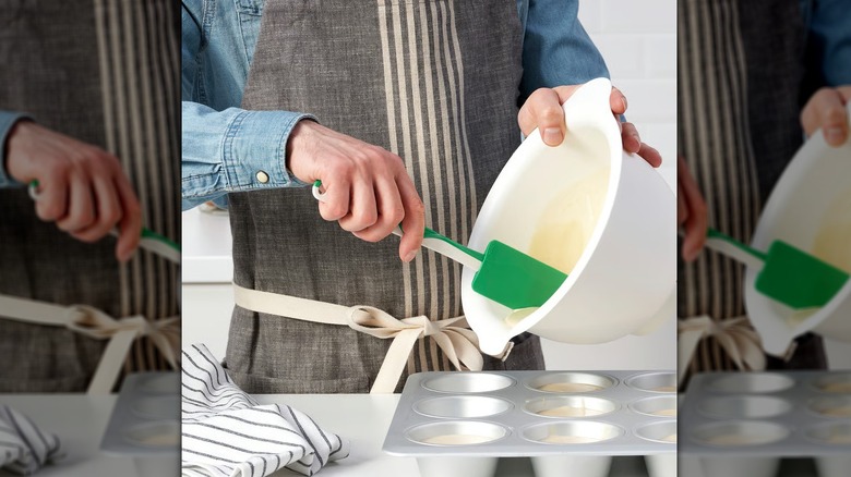 Person using a green GUBBRÖRA rubber spatula to scoop batter into a muffin tray