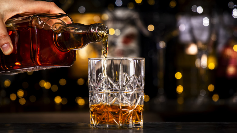 Hand pouring Bourbon into glass