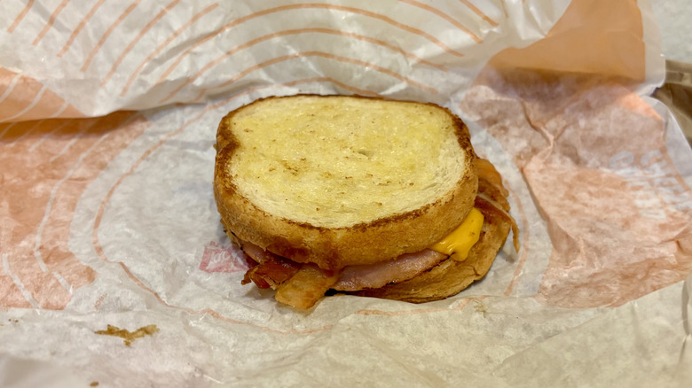 A Supreme Sourdough Breakfast Sandwich from Jack in the Box sitting on its wrapper