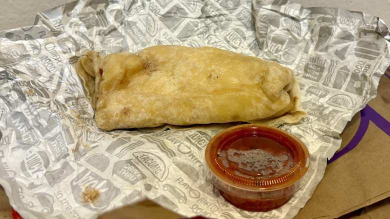 A Meat Lovers Burrito from Jack in the Box on its wrapper next to some salsa