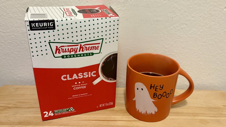 A box of Krispy Kreme Classic Coffee K-Cups, next to a coffee cup with Krispy Kreme Classic coffee inside