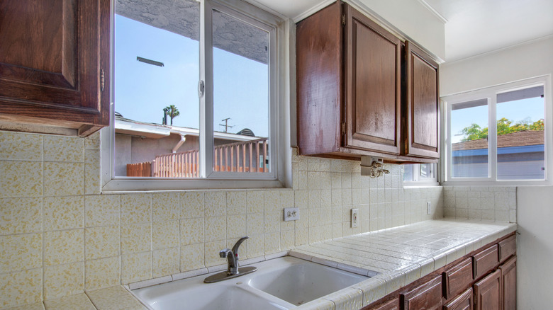 A kitchen with outdated cabinets and backsplash