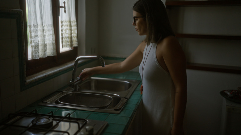 A woman in a kitchen with little natural light