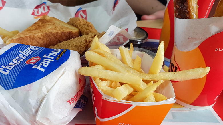 A carton of Dairy Queen fries next to a cheeseburger