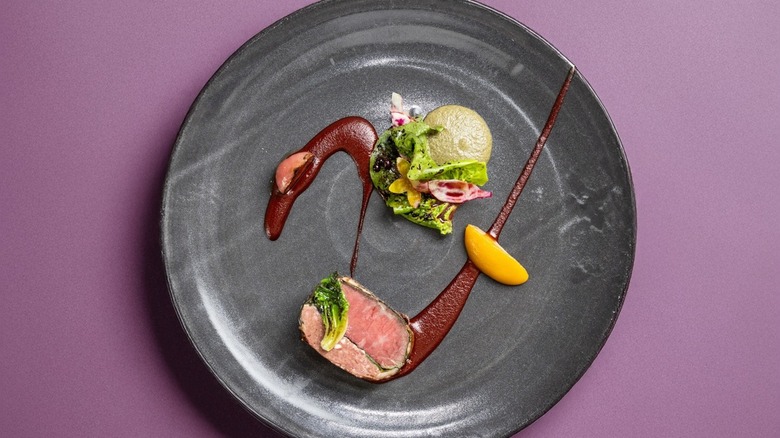 Elegant charcoal-hued plate of beef filet with red wine sauce and potatoes