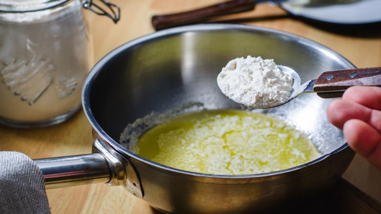 Pot with melted butter and flour being held up on a spoon