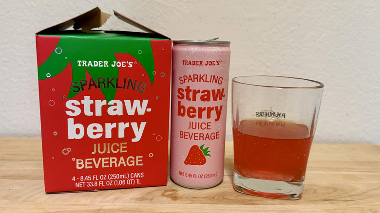 A glass of Sparkling Strawberry Juice next to its can (next to its box)