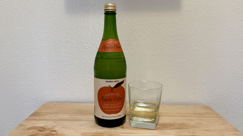 A glass of Sparkling Apple Cider next to its bottle.