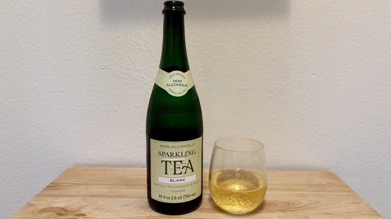 A glass of Non-Alcoholic Blanc Sparkling Tea next to its bottle.