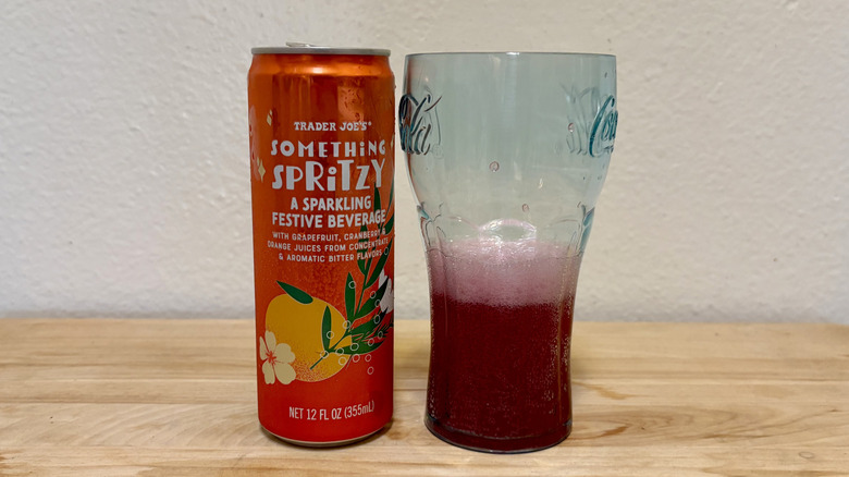 A can of Trader Joe's Something Spritzy next to a glass with red liquid.