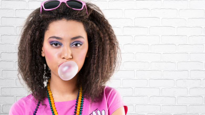 A person dressed in 1908s clothing blowing a bubblegum bubble