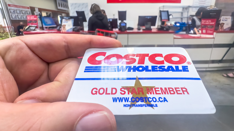 A person holding a Costco membership card at a Costco warehouse