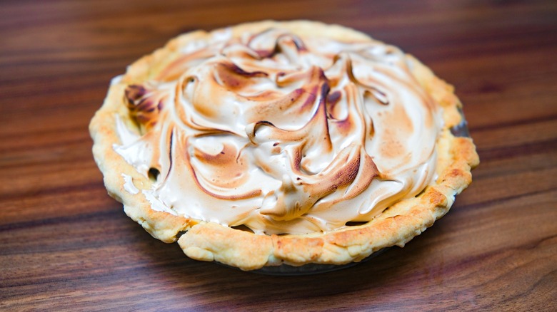 butterscotch pie with meringue topping on dark wooden table
