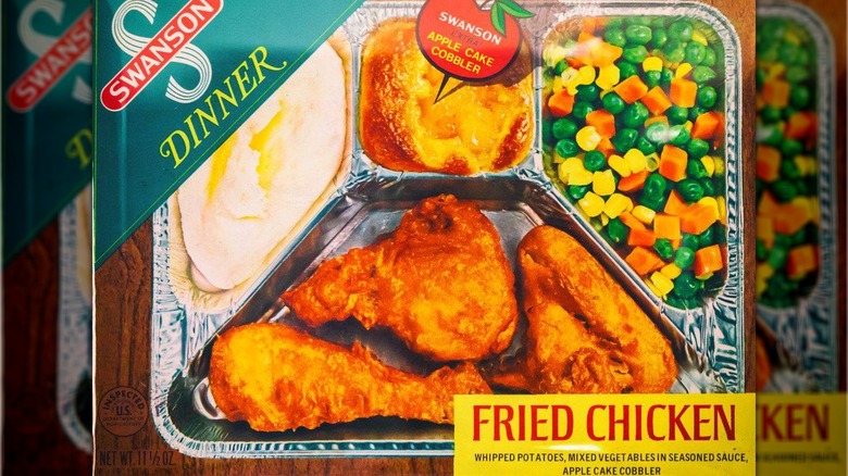 Box from Swanson TV dinner featuring fried chicken, whipped potatoes, a corn-carrot-pea mix, and apple cobbler in a foil tray