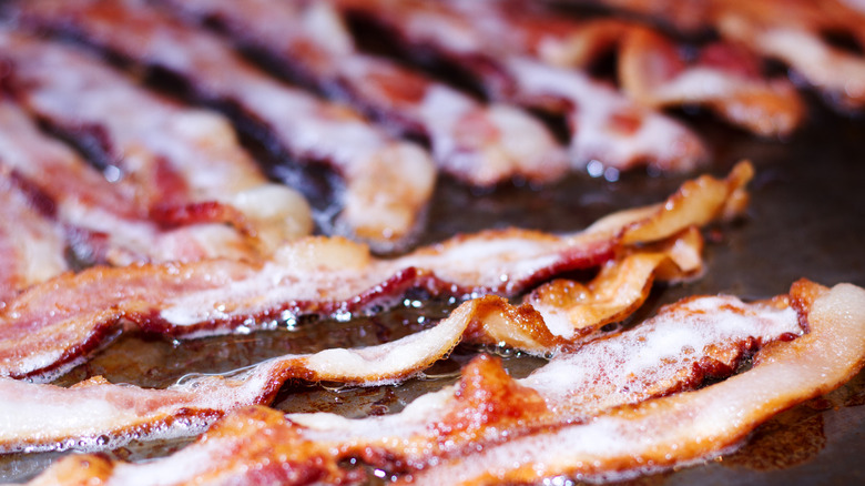 Bacon being cooked and rendering fat