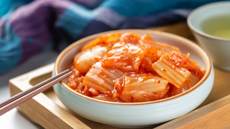 A bowl of kimchi served on a wooden tray