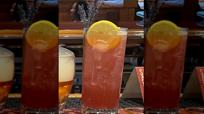 Outback Steakhouse's Blueberry lavender Lemonade cocktail on a wooden bar top with mirrored border