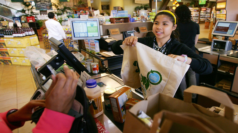 A cashier loads purchases into a reusable bag at Whole Foods Market