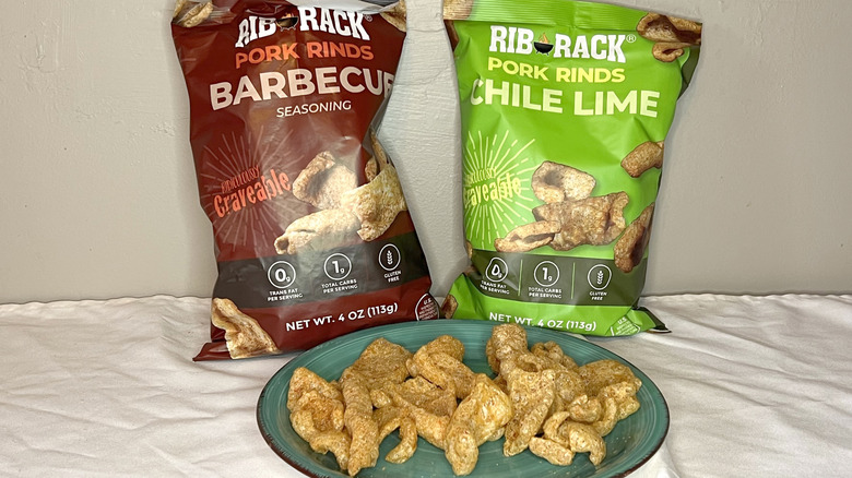 Two bags of Rib Rack pork rinds with pieces on a green plate