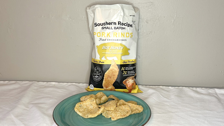 A yellow and white bag of Southern Recipe Small Batch Hot Honey Pork Rinds with pieces on a green plate
