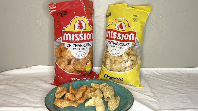 Two bags of Mission Chicharrones with pieces of rinds on a green plate