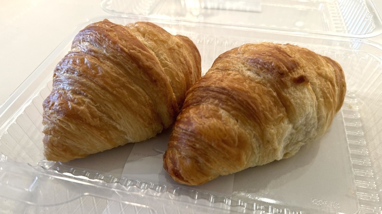 Two Publix croissants in a clear plastic container on a white table