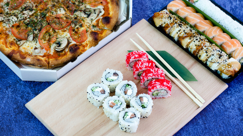 Veggie pizza next to sushi rolls