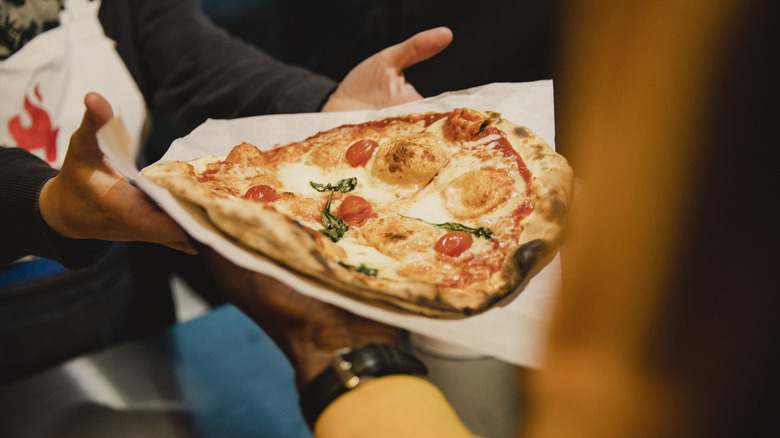 person handling margherita pizza