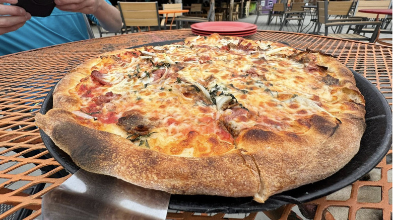 close up of entire reindeer sausage pizza sitting on a table with a spatula