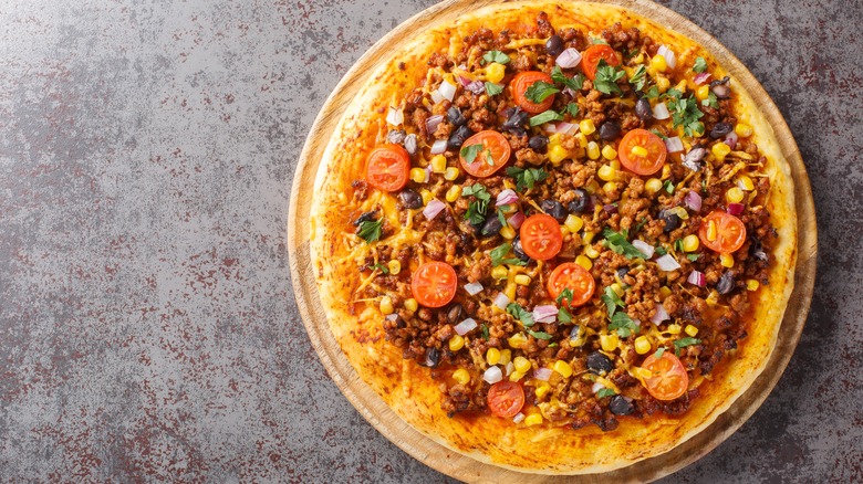 Pizza topped with various taco toppings