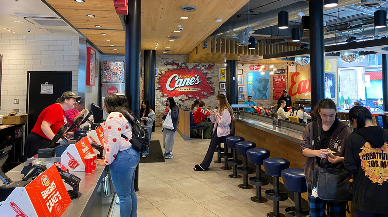 Interior of Raising Cane's showing customers at counter waiting for food