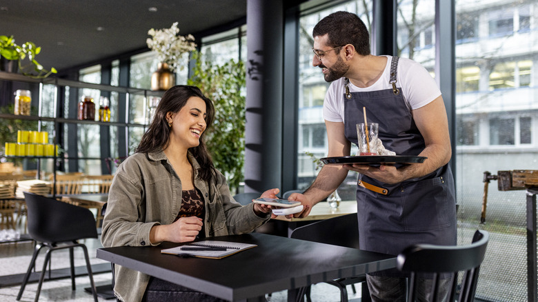 server takes payment from customer at a table