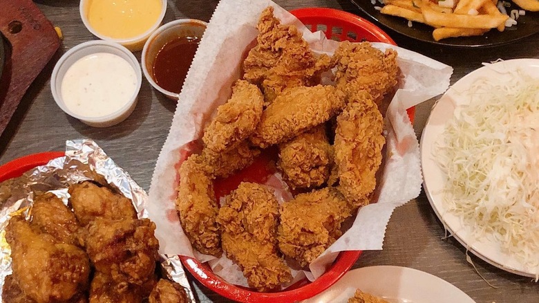 A basket of fried chicken from KoKo Chicken & BBQ surrounded by side dishes and sauces