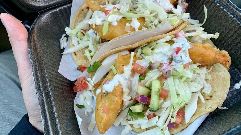 A person holding a plate of fish tacos from Kiko's Place in San Diego
