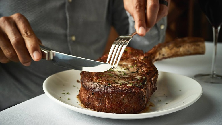Person dining on luxurious tomahawk steak
