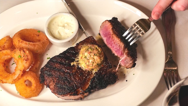 Person cutting into aged ribeye steak