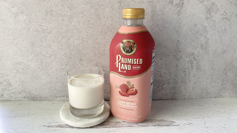 Promised Land Dairy Very Berry Strawberry Whole Milk in the original packaging and in a glass on a white marble coaster
