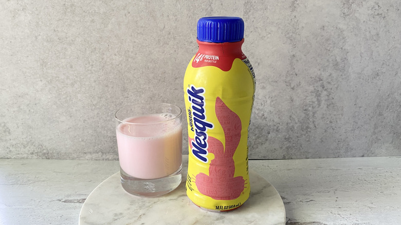 Nesquik Strawberry Flavored Low-Fat Milk in the original packaging and in a glass on a white marble coaster